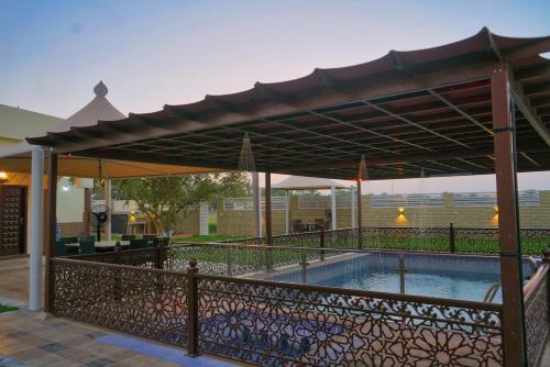 uma piscina debaixo de uma pérgola ao lado de uma cerca em Elaf Resort 4 Bed room luxury resort em Al Muladdah