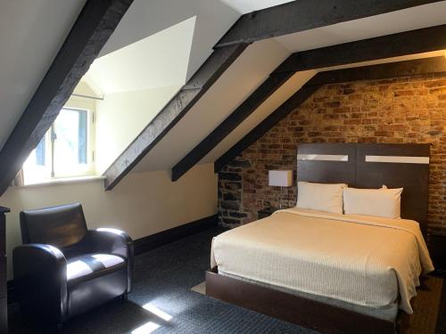 a bedroom with a bed and a chair in a attic at Hôtel Sainte-Anne in Quebec City