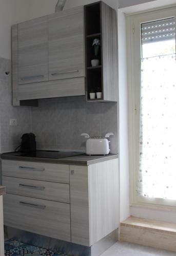a kitchen with white cabinets and a window at Smile - appartamento con giardino in Cagliari