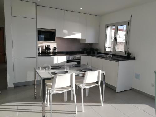 a white kitchen with a table and chairs in it at Pearl of Nazaré in Nazaré