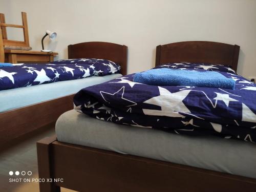 two beds in a room with blue and white blankets at Penzion DUHET in Hulín