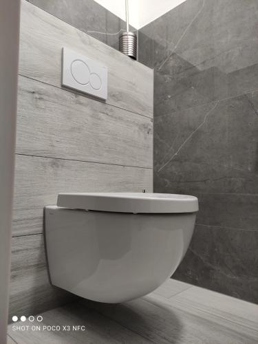 a white toilet in a bathroom with a sign on the wall at Penzion DUHET in Hulín