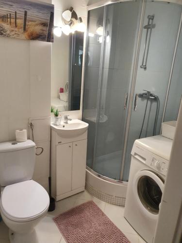 een badkamer met een douche, een toilet en een wasmachine bij Mieszkanie na Orlej 300 metrów od plaży! in Gdańsk
