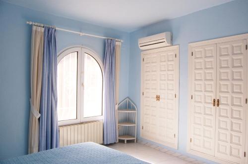1 dormitorio con paredes azules, ventana y puertas blancas en CASA VIDA, villa encantadora con vistas al mar, en Benitachell