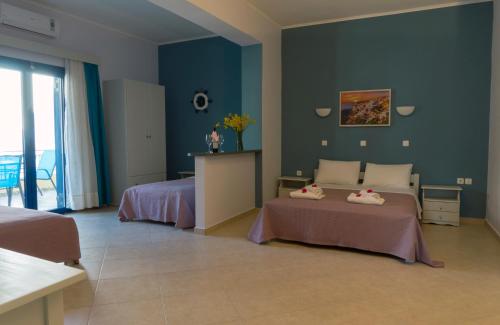 a bedroom with two beds and a blue wall at Hotel Loukas Vrachos in Paralia Vrachou