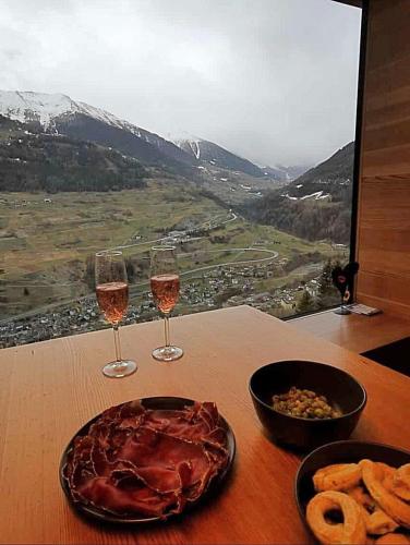 a table with two glasses of wine and a plate of food at Chalet Le Biolley in Orsières