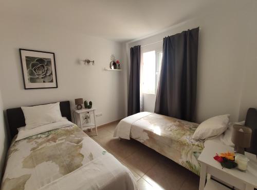 1 dormitorio con 2 camas y ventana en Vivienda Vacacional Helios - Penthouse Deluxe, en Tazacorte