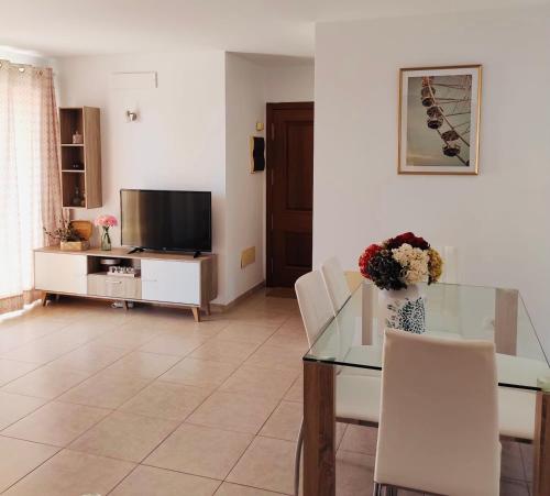 ein Wohnzimmer mit einem Glastisch und einem TV in der Unterkunft Vivienda Vacacional Helios - Penthouse Deluxe in Tazacorte