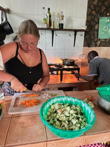 a woman cutting up vegetables on a cutting board at HOMELAND SWAHILI LODGE Nungwi Backpacker Apartments BUDGET in Nungwi