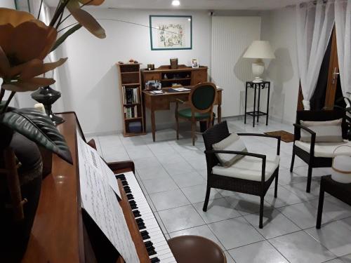 Suite hauteurs de Vichy في Creuzier-le-Vieux: غرفة معيشة فيها بيانو وطاولة وكراسي