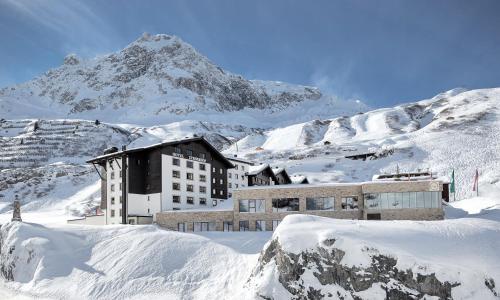a building in the snow with a mountain in the background at Hotel Zürserhof in Zürs am Arlberg