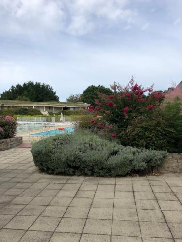 Saint-André-des-EauxにあるAppartement Golf International de la Bauleの花の咲く庭園、スイミングプールを提供しています。