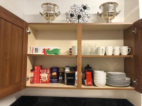 een keukenkast met borden, kopjes en borden bij Belfast Duplex Apartment No Parties in Belfast