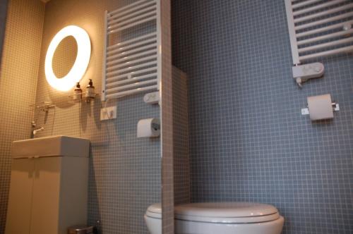 een badkamer met een toilet, een spiegel en blauwe tegels bij ROOOm Kortrijk in Kortrijk
