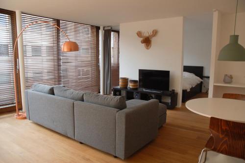 uma sala de estar com um sofá e uma televisão em ROOOm Kortrijk em Kortrijk