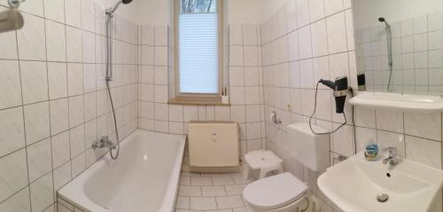 a white bathroom with a sink and a toilet and a tub at Kunstgasse 11, Wohnung 10 in Altenburg