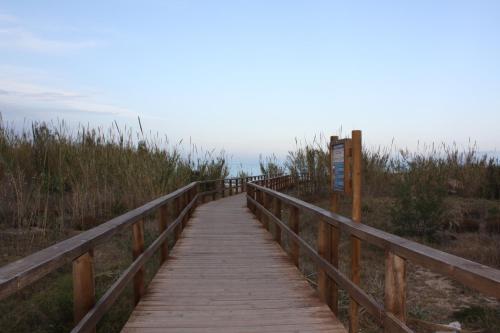 een houten promenade door het zand aan het strand bij Hotel Doña Isabel in Torrellano