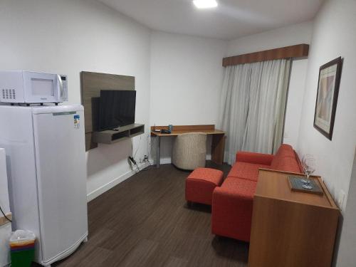 a living room with a red couch and a tv at Flat Space Valley - Para 2 Pessoas in São José dos Campos