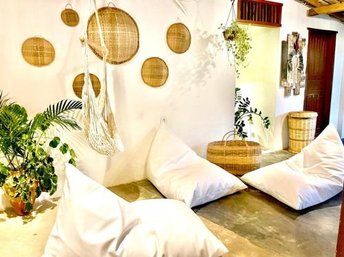 a living room with white pillows and baskets at Pousada Corais Do Sul in Caraíva