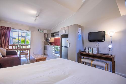 a bedroom with a bed and a kitchen and a living room at Turangi Leisure Lodge in Turangi