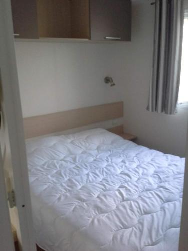 een wit bed in een kamer met een raam bij Stacaravan Bredene met tuin nr 2126 in Bredene