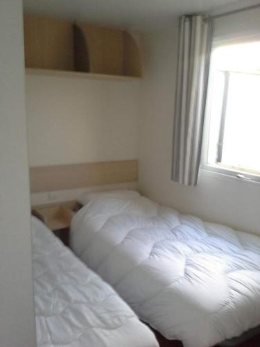 sypialnia z 2 łóżkami i oknem w obiekcie Stacaravan Bredene met tuin nr 2126 w mieście Bredene