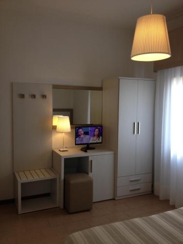 a room with a bedroom with a desk and a television at Hotel Lucerna in Castiglione della Pescaia