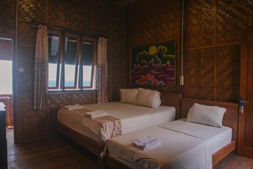 two beds in a room with wooden walls at Freddies Santai Sumurtiga in Sabong