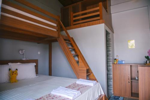 a bedroom with a bunk bed with a ladder at Freddies Santai Sumurtiga in Sabong