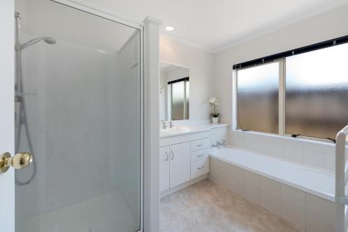 a bathroom with a shower and a tub and a sink at Mount Holidaze - Mt Maunganui Holiday Home in Matapihi