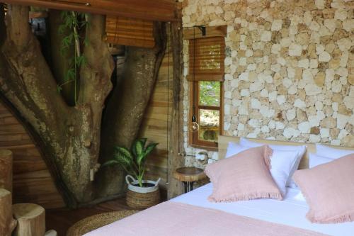a bedroom with a bed and a tree in it at Roots Tree House in Ungasan