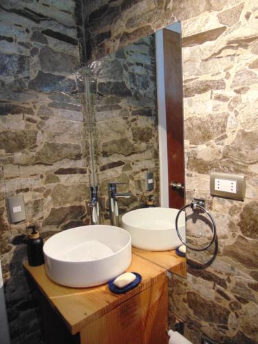 two sinks in a bathroom with a stone wall at Cabañas Casa Torres in Curacautín