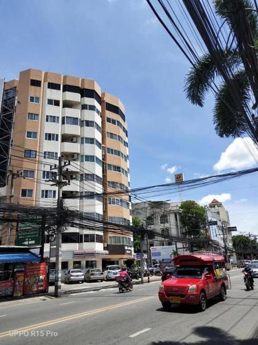a red van driving down a city street with a building at Chill Chill at Nimman in Chiang Mai