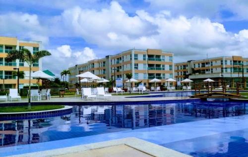 einen Pool mit Stühlen und Sonnenschirmen in einem Resort in der Unterkunft Muro Alto Condomínio Clube - Porto de Galinhas in Porto De Galinhas
