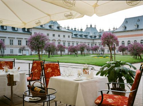 a patio area with tables, chairs and umbrellas at Schloss Hotel Dresden Pillnitz in Dresden