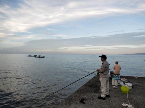 a man standing on a pier holding a fishing pole at Izu Shirada Villa 伊豆白田家 in Higashiizu