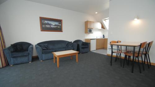 uma sala de estar com um sofá, uma mesa e cadeiras em ASURE Christchurch Classic Motel & Apartments em Christchurch