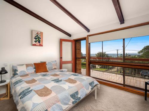 a bedroom with a bed and a large window at Cloud Nine Gerringong in Gerringong