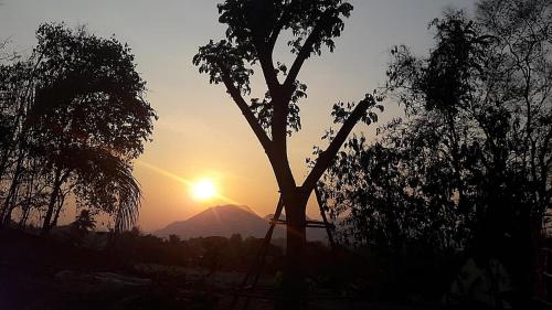 a silhouette of a mountain with the sun in the background at Homestay Chiangrai in Chiang Rai