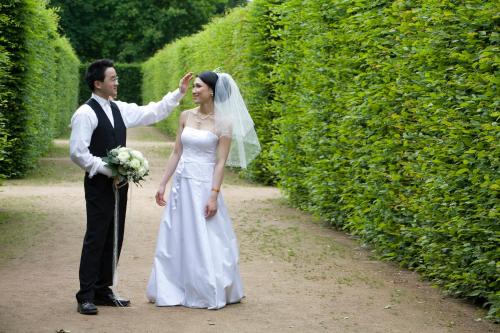 a bride and groom standing in front of a hedge at Schloss Hotel Dresden Pillnitz in Dresden