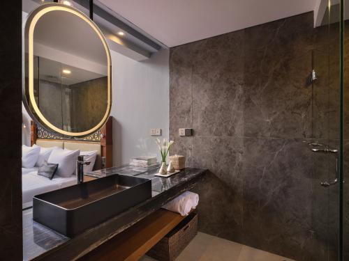 La salle de bains est pourvue d'un lavabo noir et d'un miroir. dans l'établissement Kayumas Seminyak Resort, à Seminyak