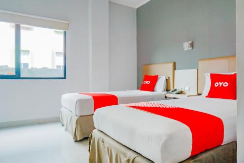 Capital O 90244 Hotel Antara في جاكرتا: سريرين في غرفة الفندق مع وسائد حمراء