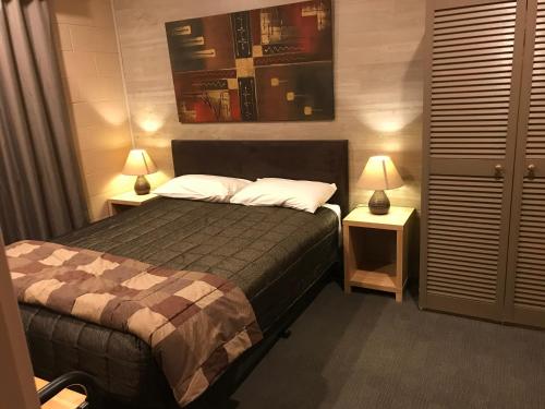 ベリデールにあるCottonwood Lodgeのベッドルーム1室(ベッド1台、ランプ付きテーブル2台付)