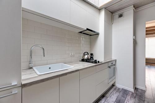 a kitchen with white cabinets and a sink at Platinium Garncarska Old Town in Gdańsk