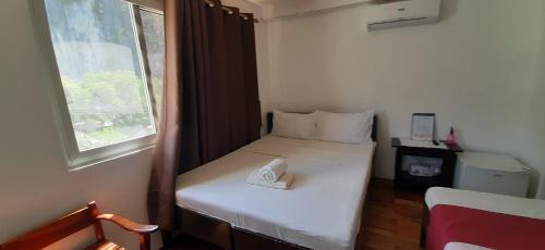 a small bedroom with a white bed and a window at A Place to Remember El Nido in El Nido