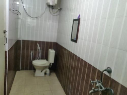 La salle de bains est pourvue de toilettes et d'un miroir. dans l'établissement Hotel Harish, à Rameswaram
