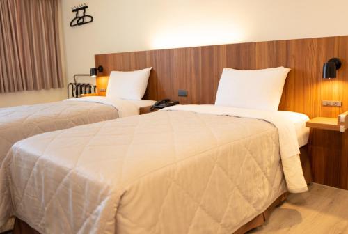 a hotel room with two beds with white sheets at Bowa Hotel Penghu in Magong