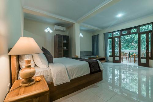 a bedroom with a bed and a lamp on a table at Vaneka Garden House in Ubud