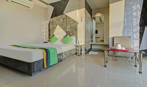 a bedroom with a bed and a table and a chair at Treebo Glassotel Near Ruby Hospital in Kolkata