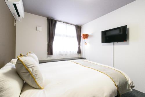 a bedroom with a white bed and a flat screen tv at JP INN Kyotoeki Kita Gakurincho in Kyoto